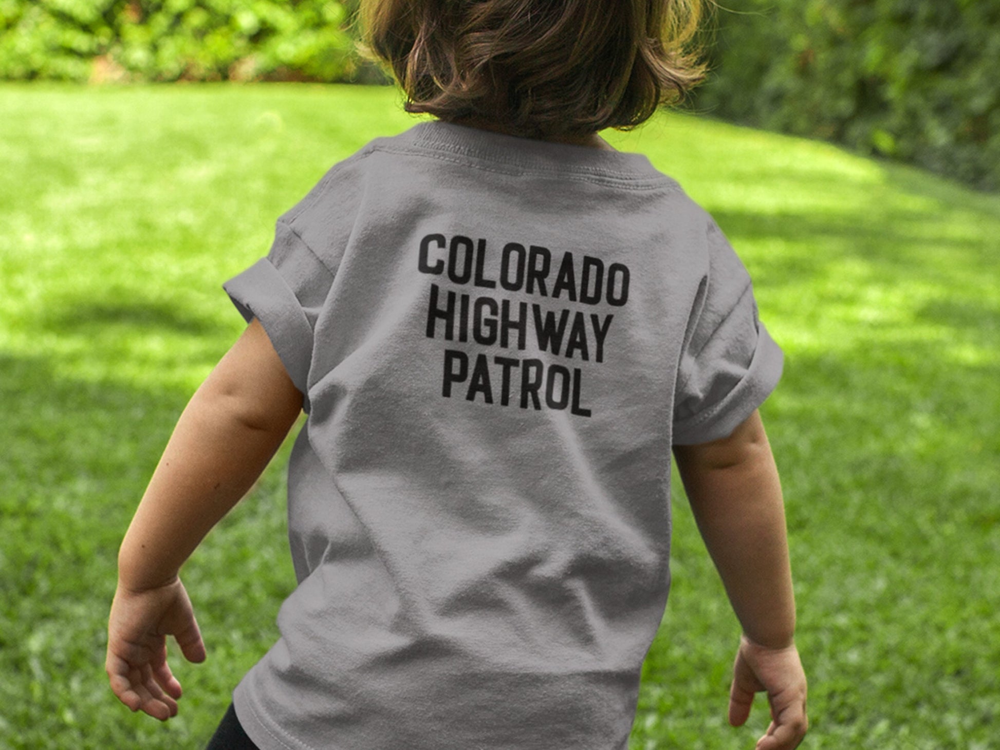 Back view of toddler wearing a gray t-shirt with black text that reads &#39;COLORADO HIGHWAY PATROL&#39;.