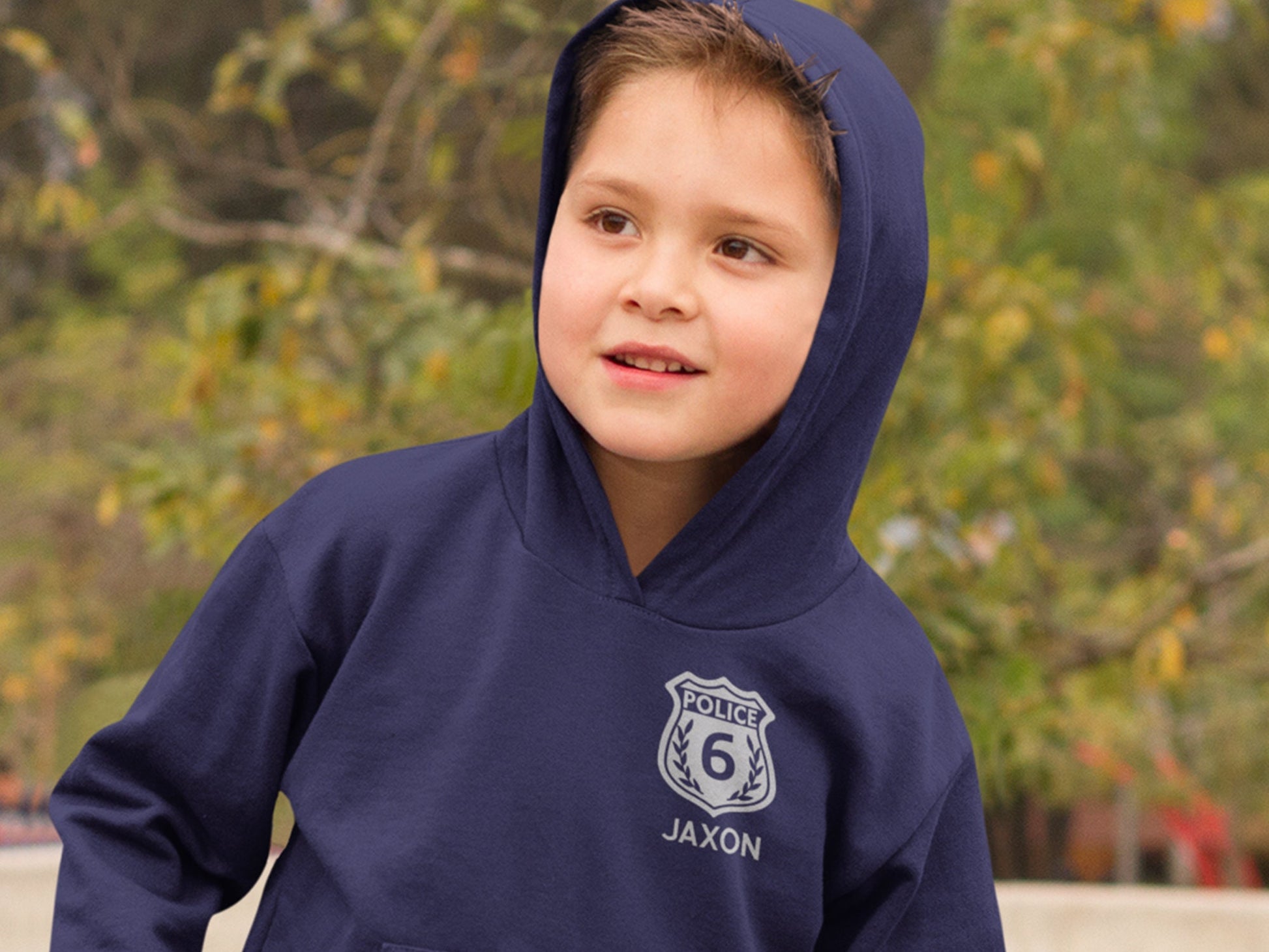 A navy blue hooded sweatshirt with a silver police badge design. The badge has the word &#39;POLICE&#39; and the number &#39;6&#39; inside. The text &#39;JAXON&#39; is below the badge.