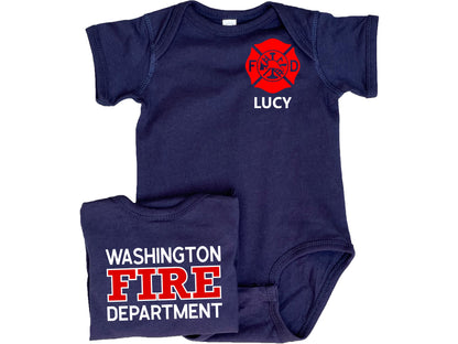 Navy blue short sleeve baby bodysuit with custom red Maltese Cross on the front. The child&#39;s name is under the Maltese Cross. A folded bodysuit shows the back with a custom fire department name with &quot;Fire&quot; and &quot;Department&quot; written underneath. The bodysuit is legless and has snaps at the crotch.