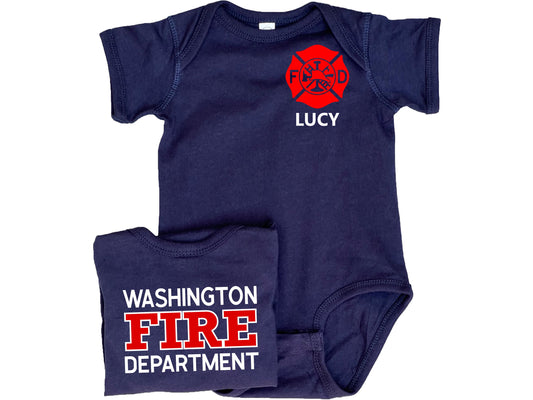 Navy blue short sleeve baby bodysuit with custom red Maltese Cross on the front. The child&#39;s name is under the Maltese Cross. A folded bodysuit shows the back with a custom fire department name with &quot;Fire&quot; and &quot;Department&quot; written underneath. The bodysuit is legless and has snaps at the crotch.