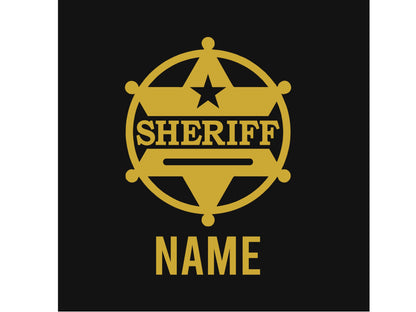 Closeup of gold sheriff badge with “name” underneath on a black background.