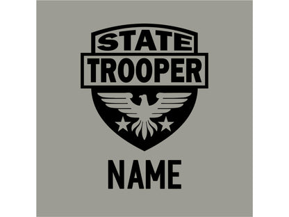 A black graphic design shows closeup of a shield with an eagle and stars. The text &#39;STATE TROOPER&#39; is at the top of the shield and the text &#39;NAME&#39; is below the shield.