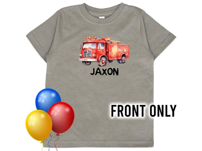 Front view of child&#39;s gray t-shirt with red watercolor design fire truck on the center chest. The child&#39;s name underneath represented by &quot;Jaxon&quot;.