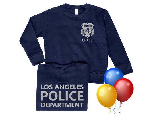 A navy blue toddler sweatshirt with a silver police badge on the front that says &#39;Police&#39; and &#39;4&#39; with the name &#39;Grace&#39; underneath. The back of the sweatshirt says &#39;Los Angeles Police Department&#39; in silver. Three colorful balloons represent a birthday theme.