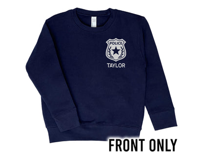 Front view of navy blue crew neck sweatshirt with silver police badge on left chest with the name &#39;Taylor&#39; underneath in silver text.