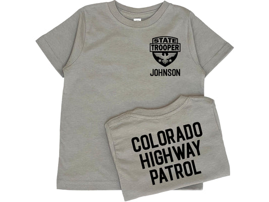 Gray toddler t-shirt with black State Trooper Badge with an eagle on the front left chest. Under the badge is &#39;Johnson&#39; as a placeholder for custom name. The shirt back has black text &#39;Colorado Highway Patrol&#39; also a placeholder for custom text.