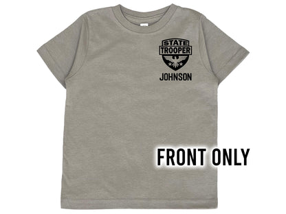 A gray short-sleeved t-shirt with a black graphic of a State Trooper badge with an eagle and the text &#39;STATE TROOPER&#39; and &#39;JOHNSON&#39; underneath in black text.