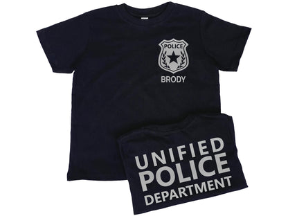 Black short sleeve t-shirt with silver police badge on left chest and the name &#39;Brody&#39; underneath in silver text. Shirt back has &#39;Unified Police Department&#39; in silver text.