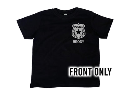 Front view of black t-shirt with silver police badge on left chest and the name &#39;Brody&#39; underneath in silver text.